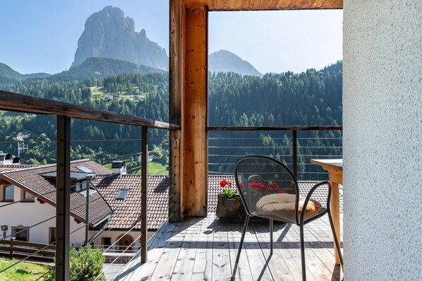 Un balcon avec vue sur les montagnes, une chaise et une table.