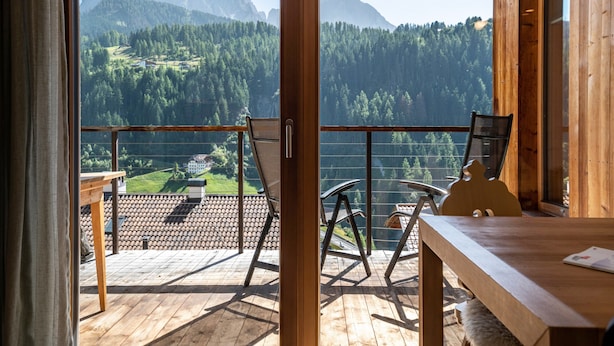 A wooden deck with chairs and a table, overlooking a mountainous landscape. - Vista Dolomites Apartment "Harmony" with Mountain View, Private Garden & Wi-Fi (S. Cristina)