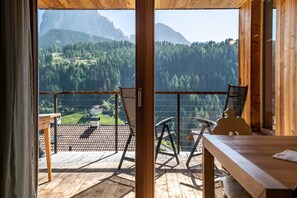 Eine Holzterrasse mit Stühlen und einem Tisch, mit Blick auf eine gebirgige Landschaft.