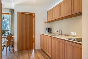 Une cuisine moderne avec des meubles en bois, une cuisinière encastrée et une fenêtre donnant sur une forêt.