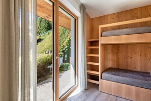 Una habitación con un amplio ventanal corredizo, estanterías de madera y un banco.