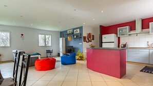 A modern kitchen with a red accent wall, a built-in island, and a seating area with a blue bean bag.