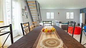 A dining area with a table, chairs, a fruit bowl, and a staircase.