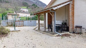 A house with a covered patio, a table with chairs, and a small kitchen area.