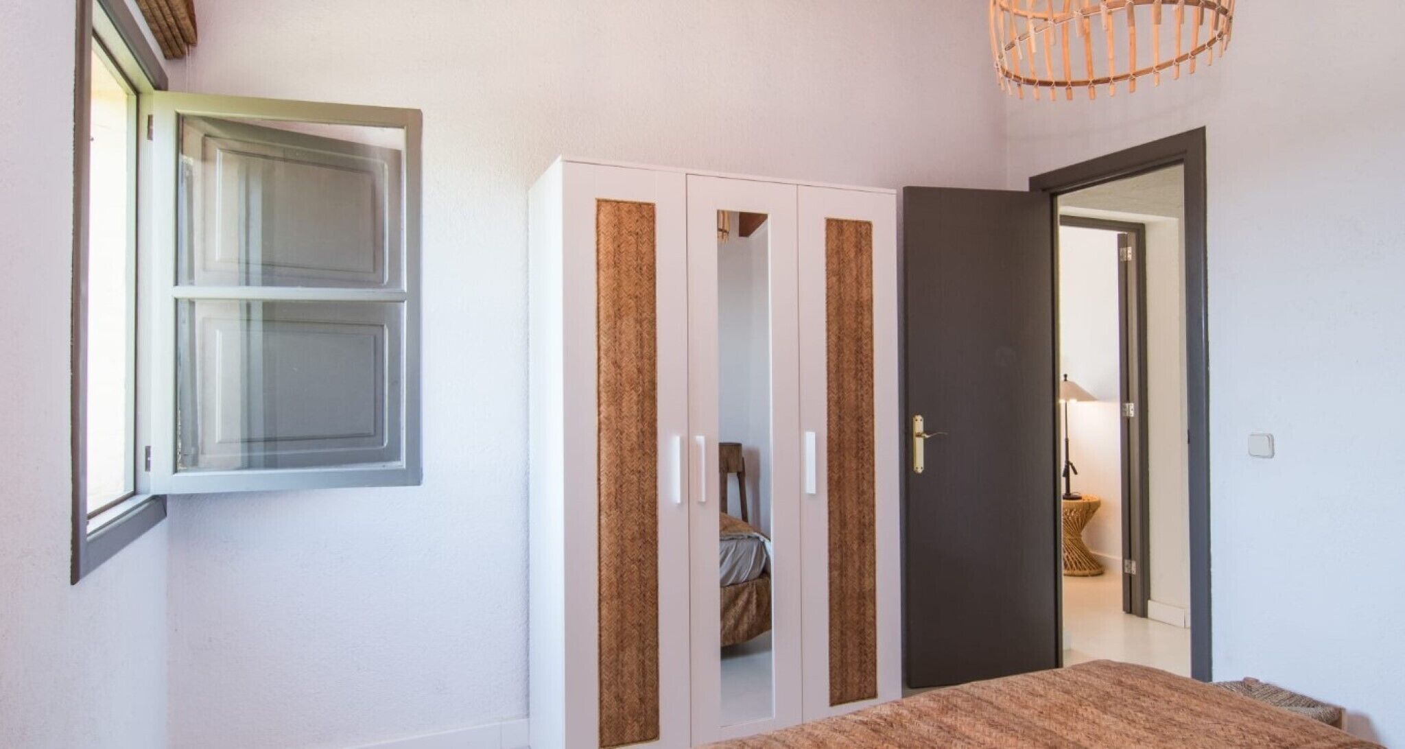 A bedroom with a bed, wardrobe, and a door leading to another room.