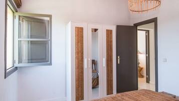 A bedroom with a bed, wardrobe, and a door leading to another room.