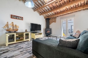 Una sala de estar con sofá, televisión, modelo de barco de madera y chimenea.