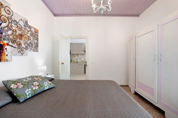 A bedroom with a bed, a wardrobe, a nightstand, and a wall art piece.