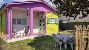 A colorful house with a covered patio, a table with chairs, and a small garden area.