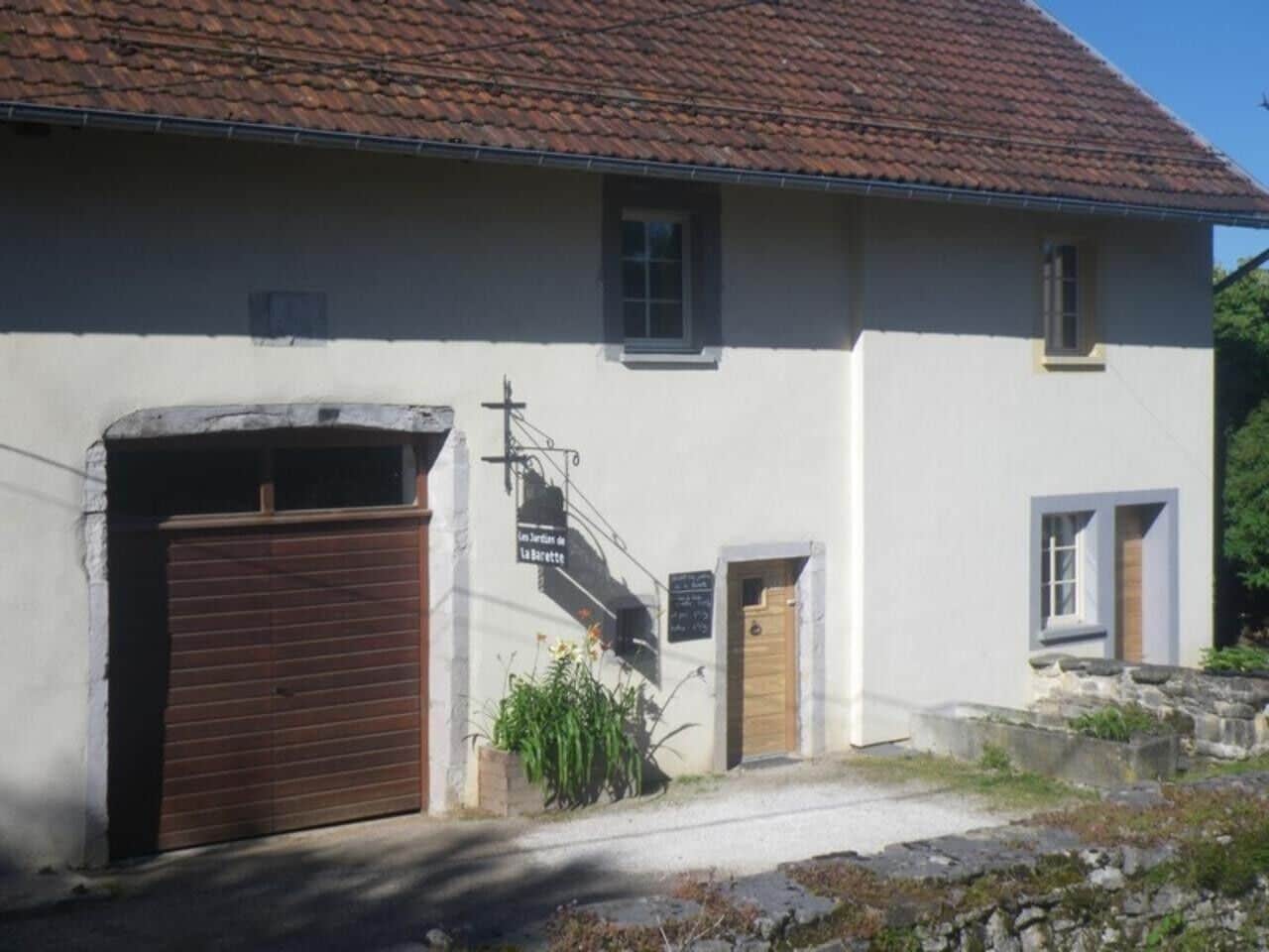 A building with a closed wooden garage door, a small entrance door, and a staircase leading to a second floor.