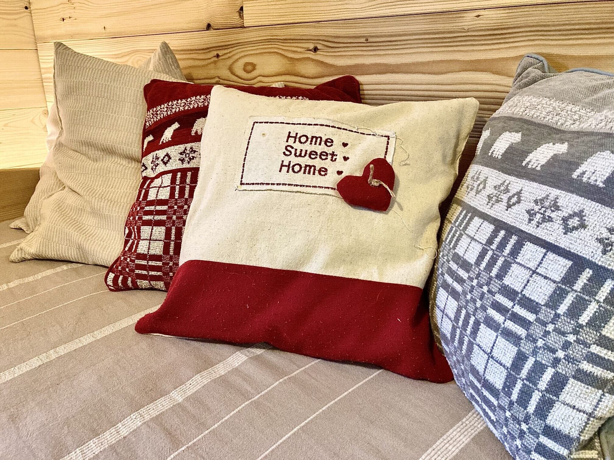 Uma cama com várias almofadas, uma delas com uma mensagem e um coração, e um cobertor estampado.