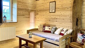 Interior de una cabaña de madera con un sofá, una mesa y una silla.