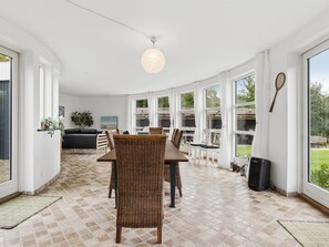 Ein geräumiger Raum mit Essbereich, großen Fenstern und einer Deckenleuchte.