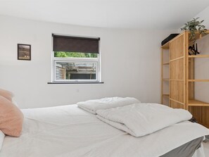 Ein Schlafzimmer mit einem Bett, einem Fenster und einem Holzregal.