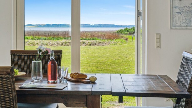 A dining table with a view of a grassy field and water body. - "Vemund" - 100m to the fjord by Interhome (Vig)