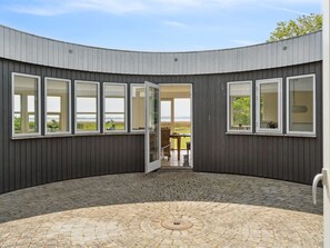 En moderne bygning med en buet facade, store vinduer og en anlagt gårdsplads.