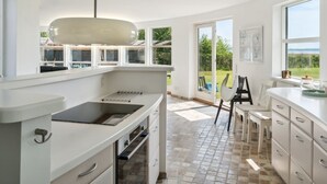 A modern kitchen with a large island, a dining area with a view, and a patio with outdoor seating. - "Vemund" - 100m to the fjord by Interhome (Vig)