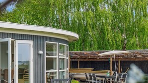 A modern house with a curved exterior, large windows, and a patio area with outdoor furniture. - "Vemund" - 100m to the fjord by Interhome (Vig)