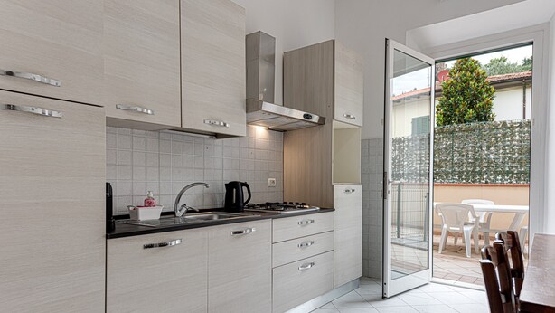 A modern kitchen with light wood cabinets, a black countertop, and a gas stove. - Apartment "Giada" with Private Terrace & Wi-Fi (Calenzano)