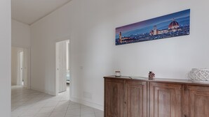 A hallway with a wooden cabinet and a cityscape painting on the wall. - Apartment "Giada" with Private Terrace & Wi-Fi (Calenzano)