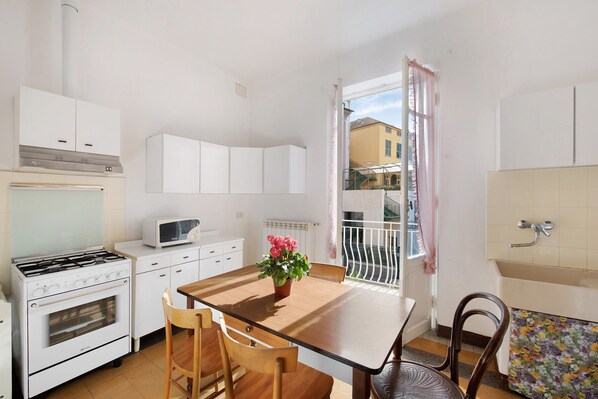 A kitchen with white cabinets, a stove, a microwave, and a dining table with chairs.