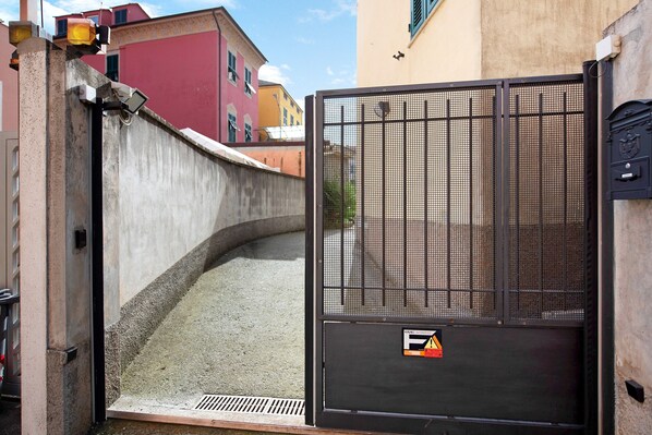 A gated entrance with a metal mesh barrier, a concrete wall, and a small drainage channel.