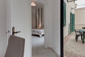 A bedroom with a bed, a door leading to a balcony, and a window with shutters.