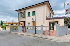 A two-story building with a gated entrance, a balcony, and a visible door.