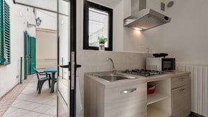 Uma cozinha moderna com fogão a gás embutido, pia de aço inoxidável e micro-ondas.