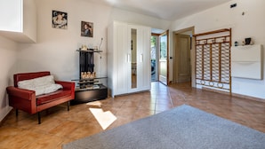 Un salon avec un canapé rouge, un meuble, un support pour télévision et une grande fenêtre.