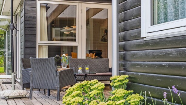 En træterrasse med udendørs møbler og forskellige planter.