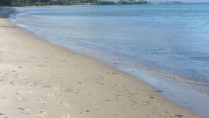 En sandstrand med fodspor og et roligt hav.