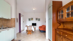 A kitchen with a dining area, a TV, and a wooden cabinet. - Holiday Home "Casa in Campagna Totale Relax" with Sea View, Private Garden & Wi-Fi (Orosei)