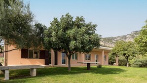 A building with a flat roof, a grassy lawn, and a tree in front. - Holiday Home "Casa in Campagna Totale Relax" with Sea View, Private Garden & Wi-Fi (Orosei)