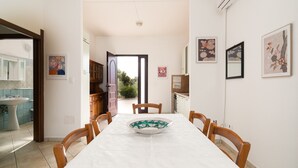 A dining area with a table, chairs, a bowl, and a view of the outdoors. - Holiday Home "Casa in Campagna Totale Relax" with Sea View, Private Garden & Wi-Fi (Orosei)