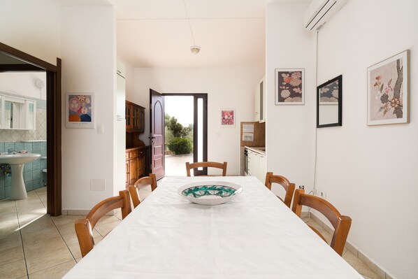 Un espace repas comprenant une table, des chaises, un bol et donnant sur l’extérieur.