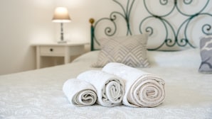 A neatly made bed with rolled white towels, a bedside lamp, and a decorative metal headboard. - Holiday Home "Casa in Campagna Totale Relax" with Sea View, Private Garden & Wi-Fi (Orosei)