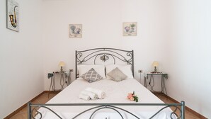 Un lit bien fait, avec un cadre en métal, deux tables de chevet avec des lampes et deux tableaux accrochés au mur.