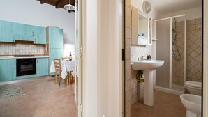 Une cuisine avec des meubles de couleur turquoise, une table à manger avec des chaises, un évier blanc et un espace douche.