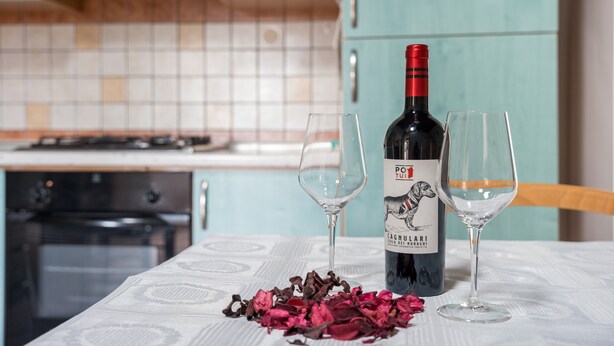 Une bouteille de vin sur une table, accompagnée de deux verres, le tout entouré de pétales de rose.