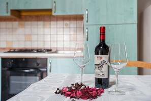 Een fles wijn op een tafel met twee glazen, omringd door rozenblaadjes.