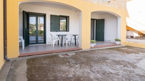 A yellow building with an open patio, white chairs, and a table. - Apartment 'Celeste' with Private Terrace, Wi-Fi and Air Conditioning (Orosei)