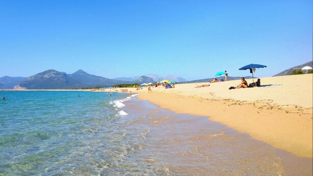 A beach with clear water, people sunbathing, and mountains in the background. - Apartment 'Celeste' with Private Terrace, Wi-Fi and Air Conditioning (Orosei)