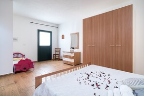 A bedroom with a bed, a dresser, a wardrobe, a chair, and a window.
