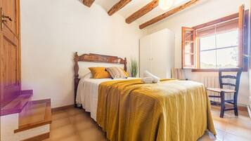 A bedroom with a wooden bed, a window with a view, and a chair.