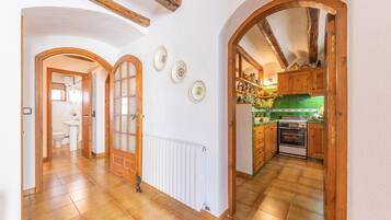 Un pasillo con puertas de madera, un radiador y una cocina con armarios de madera y una estufa.