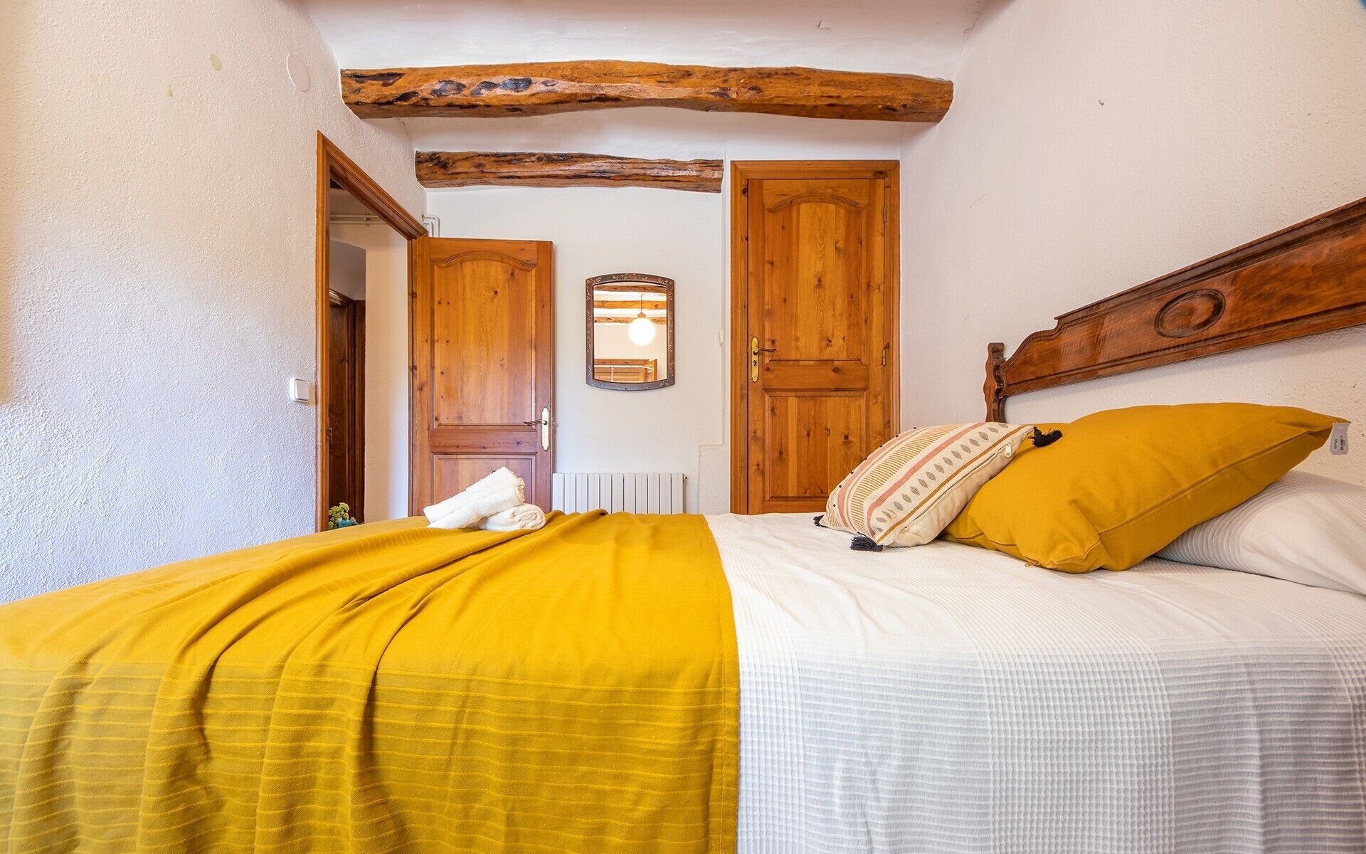Una camera da letto con un letto, porte in legno, uno specchio e un trave al soffitto in stile rustico.