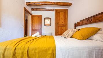 Una camera da letto con un letto, porte in legno, uno specchio e un trave al soffitto in stile rustico.
