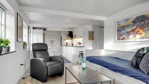 Een moderne, compacte woonruimte met een kitchenette, een slaapbank, een eettafel en een stoel.