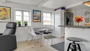 Een moderne keuken met witte kastjes, een roestvrijstalen koelkast en een fruitschaal op het aanrecht.